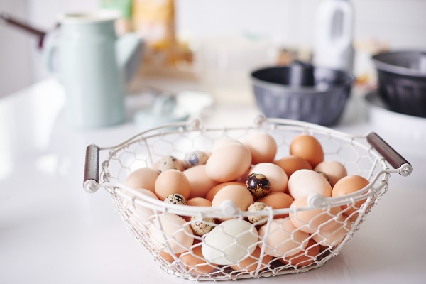 Basket of multi-coloured eggs in a white metal basket