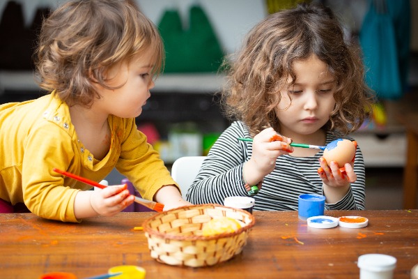 Two young children painting eggs